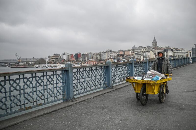A garbage collector pushes a wheelbarrow across the empty Galata bridge in Istanbul, after Turkish officials have repeatedly urged citizens to stay home and respect social distancing rules. AFP