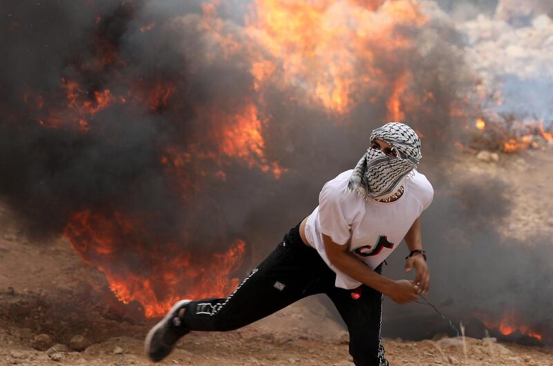 A Palestinian demonstrator throws stones during clashes with Israeli troops in the West Bank village of Soreef, near Hebron. EPA