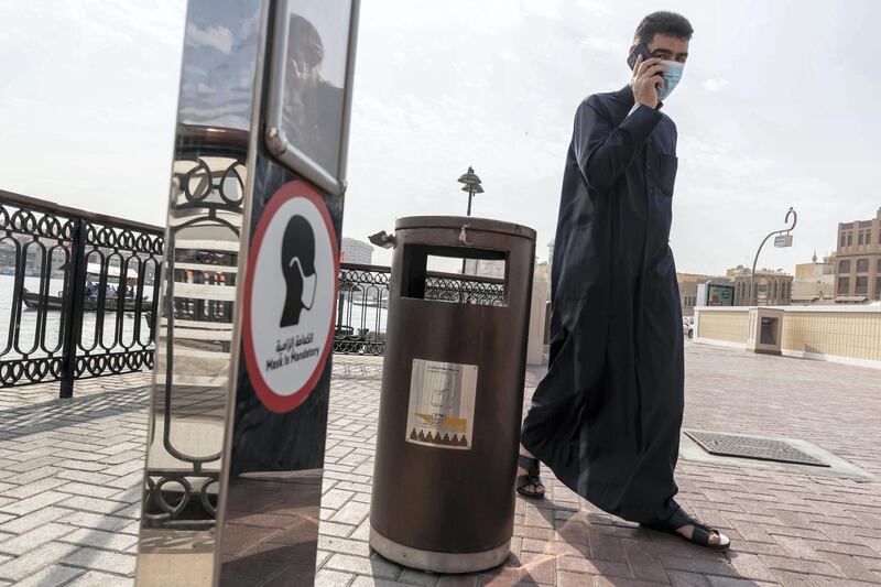 DUBAI, UNITED ARAB EMIRATES. 25 FEBRUARY 2021. COVID - 19 Standalone. Deira souk during the time of Covid. a man uses a mobile phone while still wearing his mask at the Spice Souk Abra station in Deira. (Photo: Antonie Robertson/The National) Journalist: Nick Webster. Section: National.