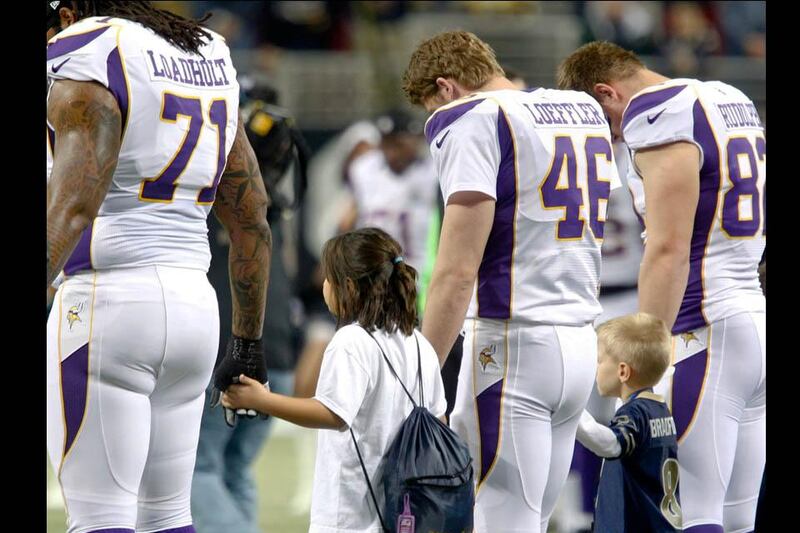 Members of the Minnesota Vikings team hold hands with children during a moment of silence for the victims of the Sandy Hook Elementary school shooting before their NFL football game against the St. Louis Rams. Sarah Conard / Reuters