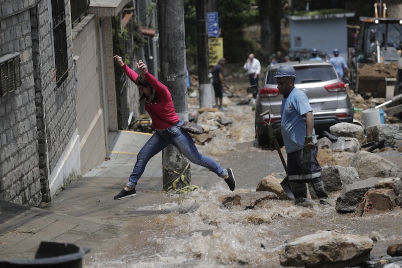 People leap over floodwaters on a street. EPA