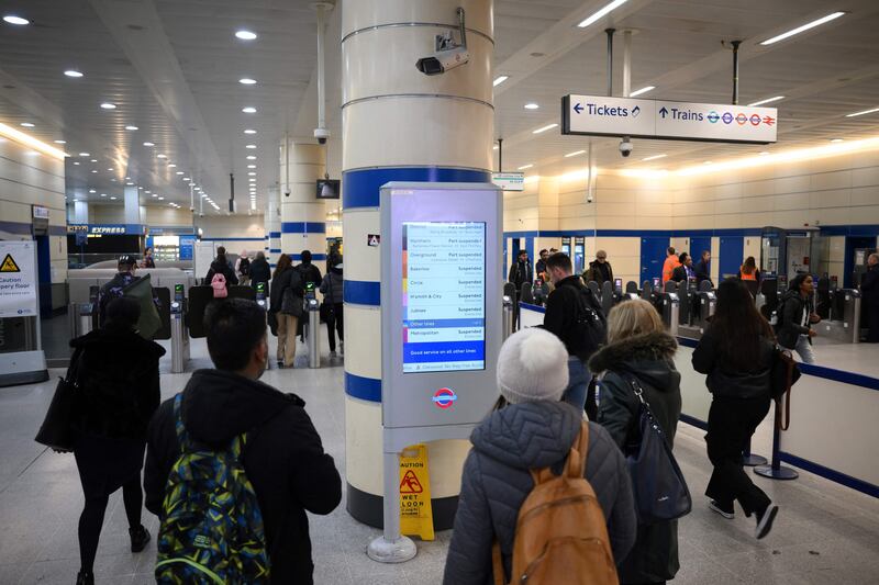Commuters check a screen announcing service disruption at Stratford Station in London. AFP