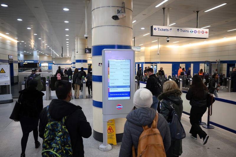 Commuters check a screen announcing service disruption at Stratford Station in London. AFP