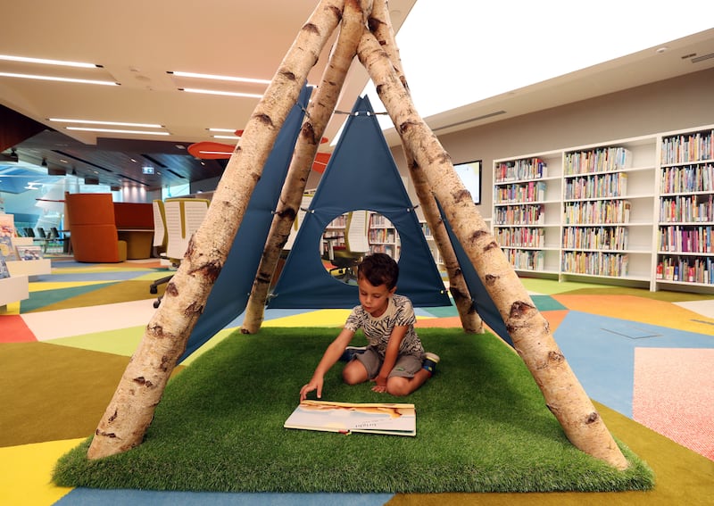 Three-year-old Evan reads a book in the library. 