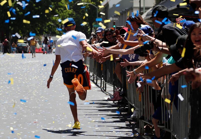 Golden State Warriors guard Stephen Curry runs down a street to greet fans along the route. John G. Mabanglo / EPA