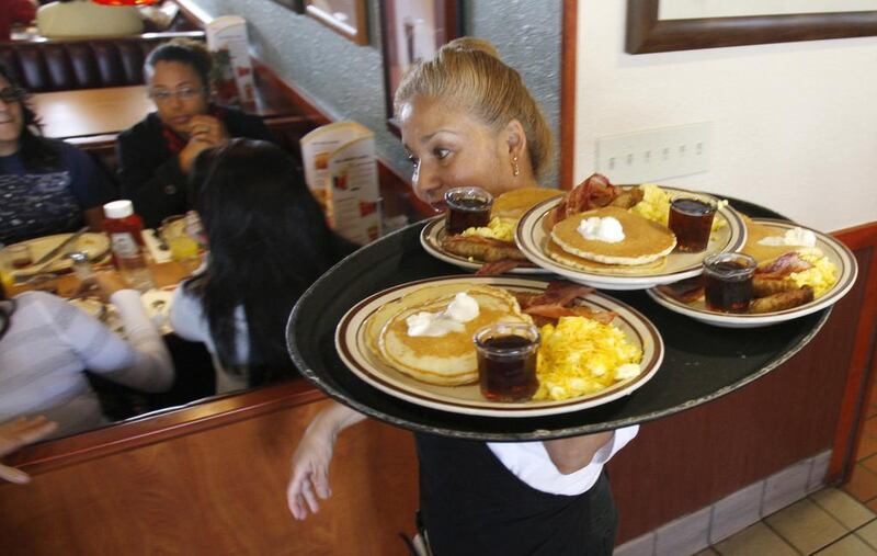 A Denny's employee carries a tray with free Grand Slam breakfasts for customers. The eaterie is heading to the Middle East. AP Photo/Alan Diaz