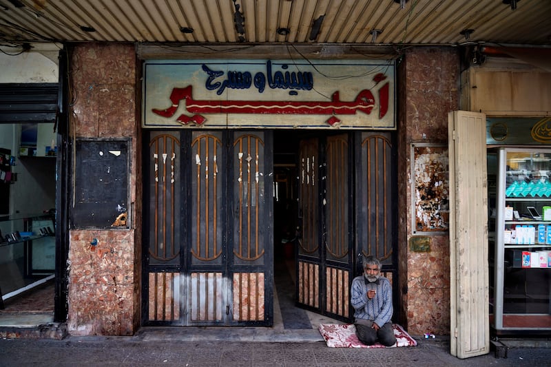 A beggar sits at the entrance of Empire Cinema in Tripoli, Lebanon. AP