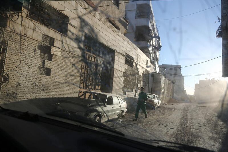 A medic runs for cover during reported regime shelling on the rebel-held town of Hamouria, in the besieged Eastern Ghouta region on the outskirts of the capital Damascus on March 7, 2018.  / AFP PHOTO / Abdulmonam EASSA