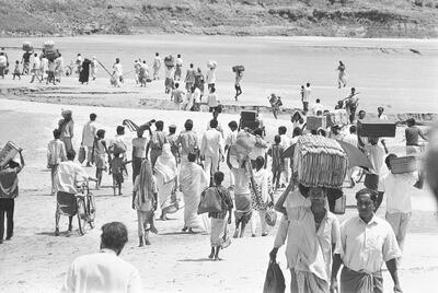 Carrying their few worldly possessions, Bengalis stream across the shallows of the River Ganges Delta at Kushtia, East Pakistan to escape from the advancing troops of the West Pakistan army fighting near Goaiubogath, April 8, 1971. Kushtia is 30 miles east of the Indian border and 105 miles northeast of Calcutta, where East Pakistan Liberation Forces appear to be controlling much of the area. (AP Photo/Michel Laurent)