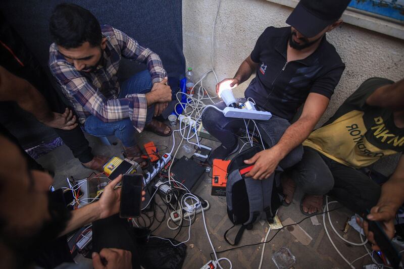 Palestinians plug their phones into portable charging stations on a street in Khan Younis, Gaza. Bloomberg
