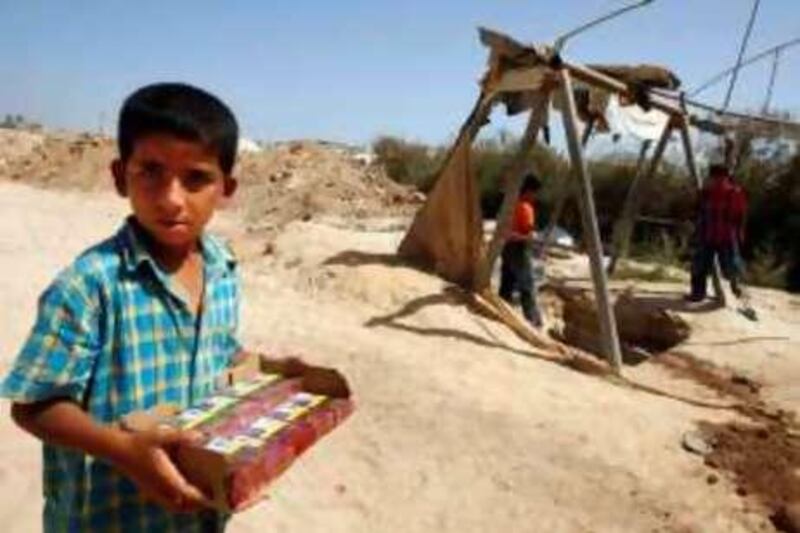 A Palestinian boy holds a box of smuggled cigarettes near the entrance of an inactive tunnel which links Egypt and the southern Gaza Strip border town of Rafah on June 21, 2010 after Israel announced it would allow into the Hamas-ruled Palestinian territory everything that cannot be used by Gaza's Hamas rulers to build weapons or fortifications, dealing a potentially fatal blow to the tunnel trade that has largely sustained the coastal enclave. AFP PHOTO/SAID KHATIB *** Local Caption ***  824349-01-08.jpg