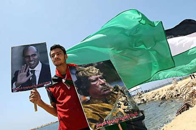 A Palestinian youth holds posters of the Libyan leader, Muammar Qadafi, and the leader's son Seif al Islam during a rally in support of the Libyan aid ship threatening to run the Israeli blockade of Gaza.