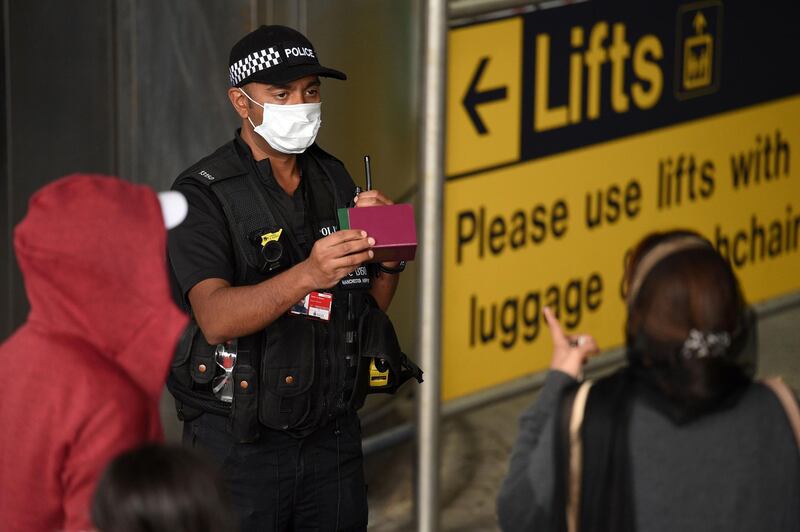 A police officer talks to passengers at Manchester Airport. AFP