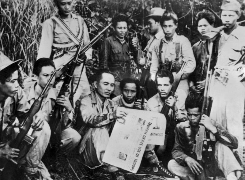 Huk guerrilla leader and founder of the Communist struggle in the Philippines, Luis Taruc, in 1950 disproves government claims of his demise by posing with a newspaper dated July 1. He is surrounded by members of his guerrilla band. AFP