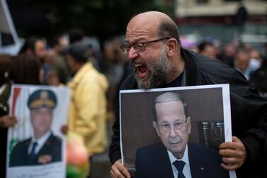 An anti-government protester holds a picture of Lebanese President Michel Aoun as he shouts slogans during a protest, in Beirut's Ashrafieh district, Lebanon, on November 26, 2020. AP