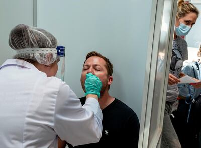 A passenger is tested at the Covid-19 test center at the airport in Frankfurt, Germany, Tuesday, Aug. 18, 2020. For passengers coming from high-risk-countries a Covid-19 test is mandatory. (AP Photo/Michael Probst)