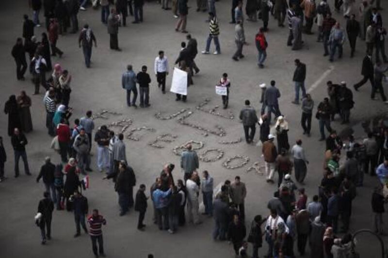 Anti-government protesters take pictures of protest art in Tahrir Square, the center of anti-government demonstrations, in Cairo, Egypt, Sunday, Feb. 6, 2011. Egypt's vice president met a broad representation of major opposition groups for the first time Sunday and agreed to allow freedom of the press and to release those detained since anti-government protests began, though Al-Jazeera's English-language news network said one of its correspondents had been detained the same day by the Egyptian military. The Arabic on the ground reads "We are the Men of Facebook". (AP Photo/Tara Todras-Whitehill) *** Local Caption ***  TTW110_Mideast_Egypt.jpg