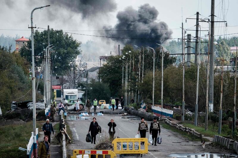 People are evacuated with their belongings as an explosion rocks a bridge over the Oskil River in the frontline city of Kupiansk in Ukraine. AFP