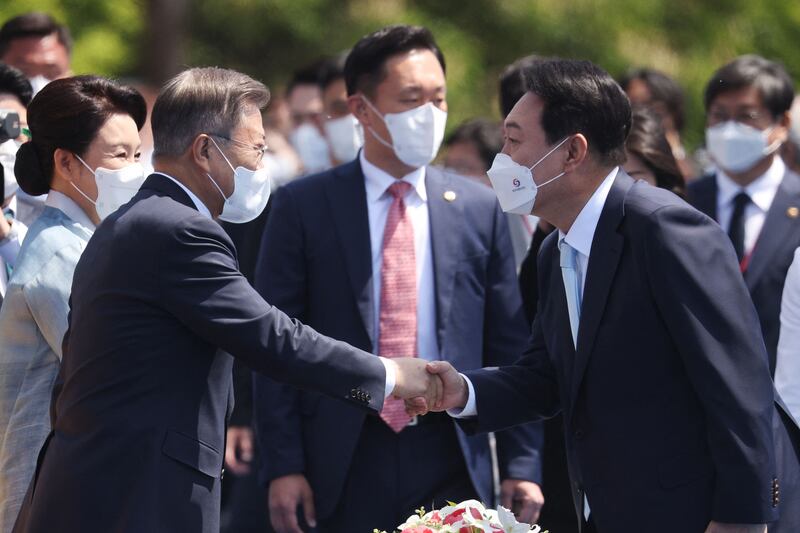 Mr Yoon shakes hands with former president Moon Jae-in upon his arrival at the ceremony. AFP