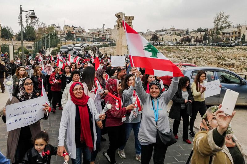 Lebanese women march with national flags during a demonstration near the Roman ruins in the eastern Bekaa Valley city of Baalbeck on October 26, 2019, on the tenth day of country-wide protests against tax increases and official corruption.  / AFP / -
