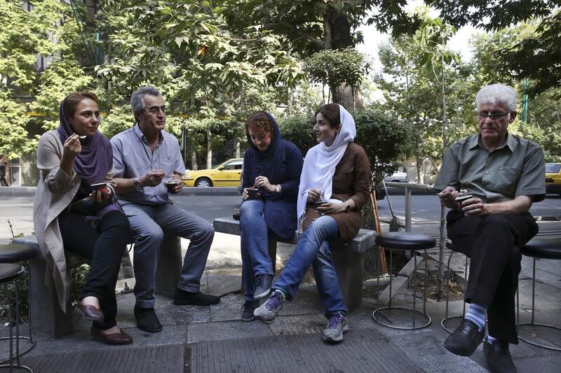 Iranians enjoy ice-cream on a sidewalk in northern Tehran. Vahid Salemi / AP