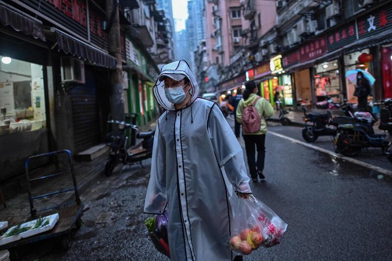 A person wearing a face mask as a preventive measure against the spread of the COVID-19 novel coronavirus carries groceries in a neighbourhood in Wuhan in China's central Hubei province on April 20, 2020. A bride in a white gown poses by Wuhan's East Lake while a grandfather swings his tiny grandson in a hammock strung between trees, and families enjoy a picnic on a sunny afternoon: Wuhan is returning to normal after enduring a 76-day quarantine. - TO GO WITH Health-virus-China-Wuhan,FOCUS by Jing Xuan Teng
 / AFP / Hector RETAMAL / TO GO WITH Health-virus-China-Wuhan,FOCUS by Jing Xuan Teng
