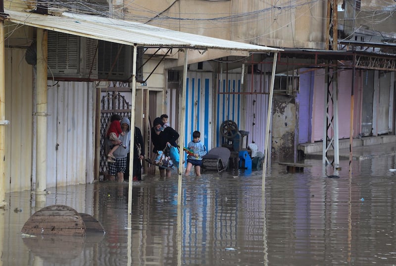 Iraqis walk in a street flooded by heavy rain in the northern city of Mosul. AFP