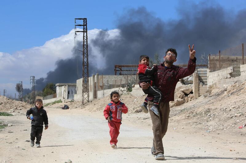 A man and his children walk towards government-held territory in Hamouria on March 16, 2018. AFP