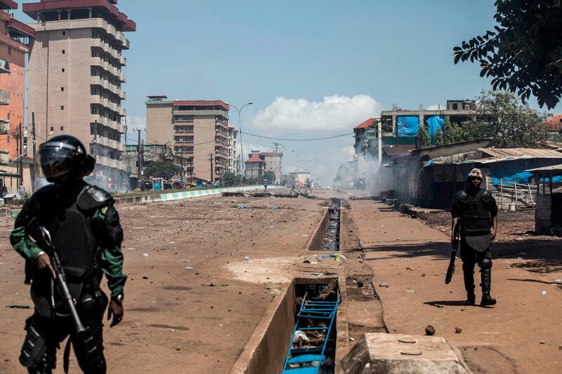 Police officers are seen in-front of protesters, as they continue to throw stones and block roads during mass protests after preliminary results were released in Conakry.  Guinea. AFP