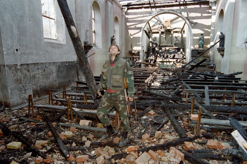 A Bosnian soldier surveys a destroyed church in Stup, in March 1993. AFP