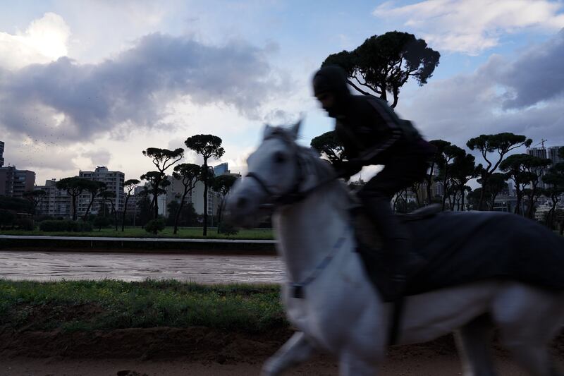 A jockey spurs his horse around the training ring on the outer edge of the track.