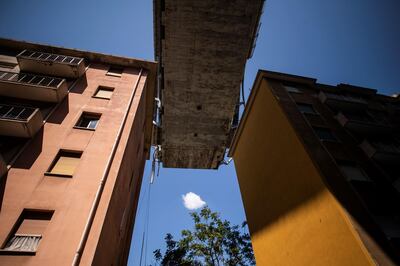 Appartment buildings are seen under the Morandi motorway bridge, two days after a section collapsed in Genoa on August 16, 2018. - A vast span of the Morandi bridge caved in during a heavy rainstorm in the northern port city on August 14, 2018, sending about 35 cars and several trucks plunging 45 metres (150 feet) onto railway tracks below and killing at least 39 people. (Photo by MARCO BERTORELLO / AFP)