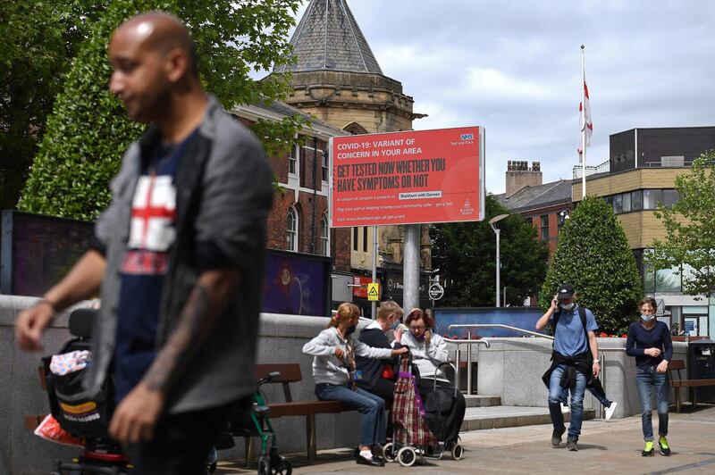 Pedestrians walk past an electronic board displaying information relating to a 'variant of concern in the area' in Blackburn, north-west England. AFP