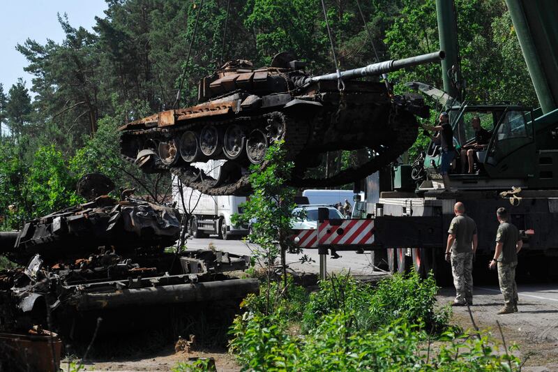 Ukrainian servicemen collect destroyed Russian tanks outside the village of Dmytrivka. AFP