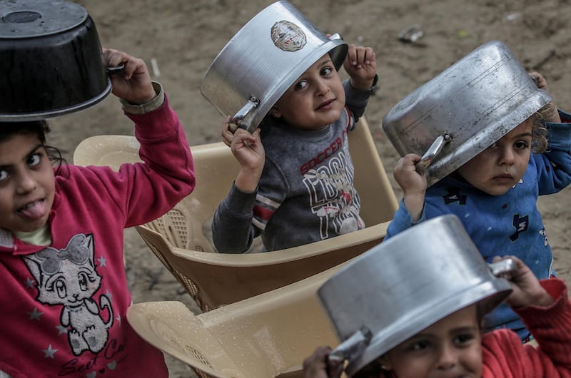 Palestinian children wait with pots to receive free food. EPA