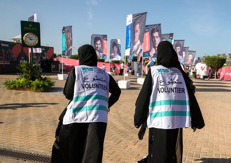 Two volunteers walk in the fan zone at Yas Marina Circuit