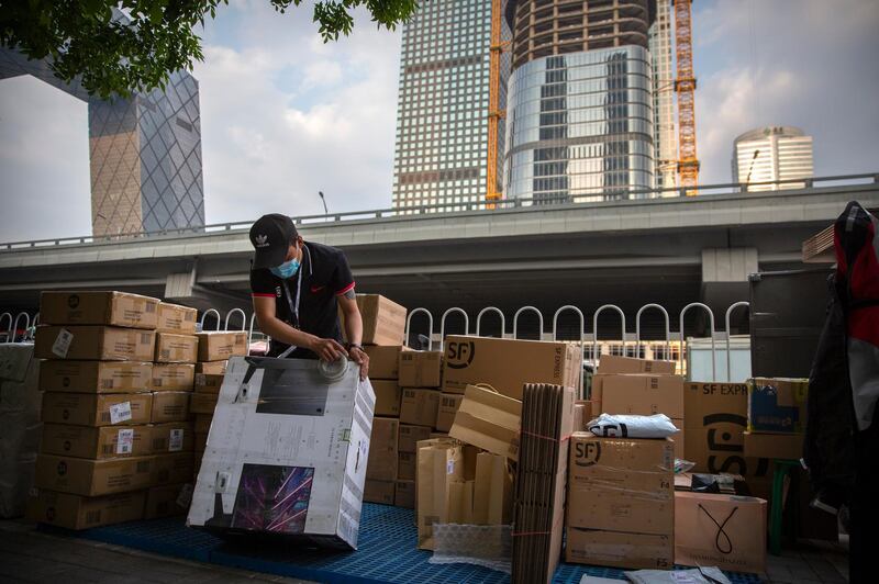 A delivery courier tapes a package along a road in the central business district in Beijing. AP Photo