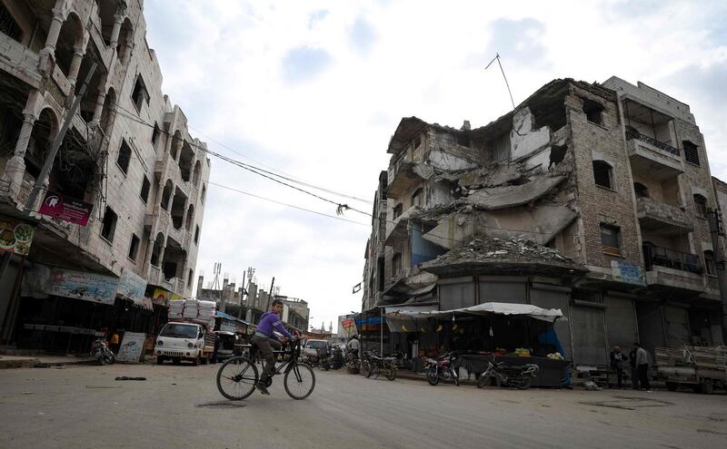 A boy rides his bicycle past damaged buildings in Idlib city. AFP