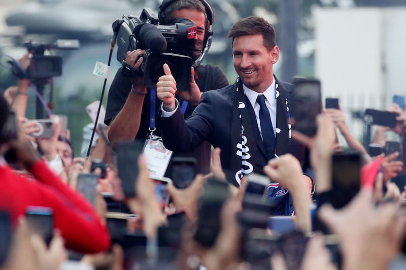 Lionel Messi gestures to fans outside the PSG stadium.