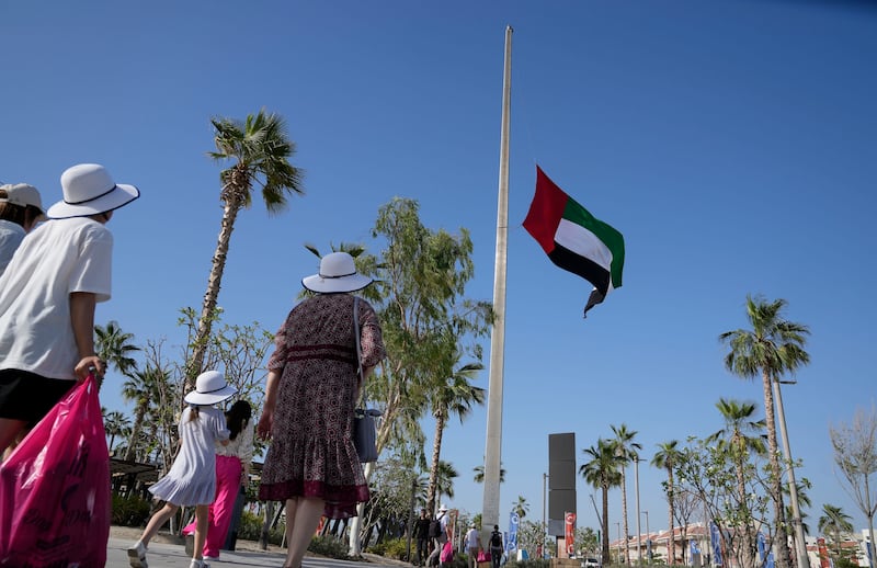 People pass by the UAE national flag, flying at half-staff, following the announcement of President Sheikh Khalifa's death. AP Photo