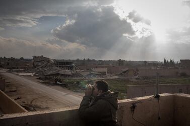 An SDF commander looks for ISIS positions from a rooftop near the front line in Bagouz, Syria. Getty Images