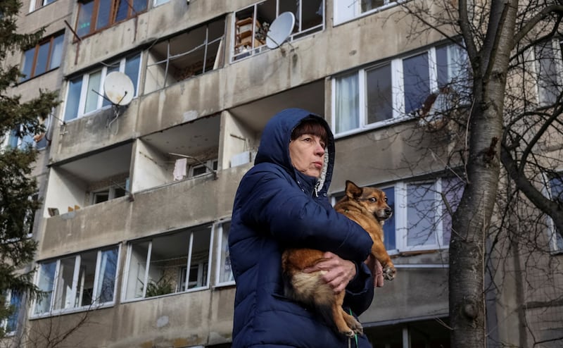 A local resident holds her dog as she stands near her apartment building damaged during a Russian missile strike in Lviv, Ukraine. Reuters