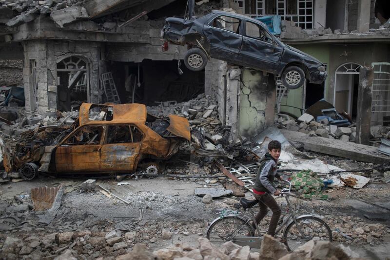 FILE - In this March 19, 2017, file photo, a boy rides his bike past destroyed cars and houses in a neighborhood recently liberated by Iraqi security forces on the western side of Mosul, Iraq. Six African nations are among the 10 worst in the world to be a child in a war zone, according to a new report by Save the Children released Thursday, Feb. 15, 2018 that looks at factors including attacks on schools, child soldier recruitment, sexual violations, killings and lack of humanitarian access. (AP Photo/Felipe Dana, File)