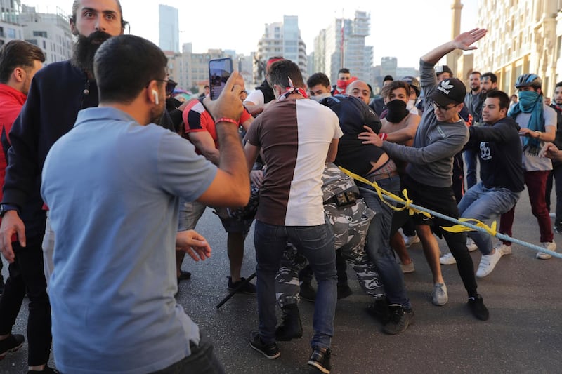 Anti-government protesters hit a police officer as they try to remove barbed wire that blocks a road leading to the parliament building in downtown Beirut. AP Photo