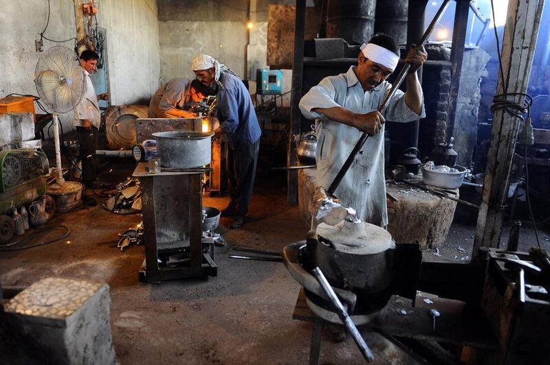 An Afghan labourer, right, pours molten aluminium into a mold at a workshop in Herat.