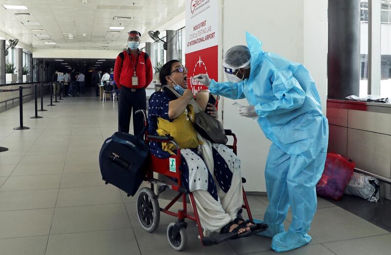 A health worker in personal protective equipment (PPE) collects a swab sample from a woman amidst the spread of the coronavirus disease (COVID-19) at Indira Gandhi International Airport, in New Delhi, India. REUTERS