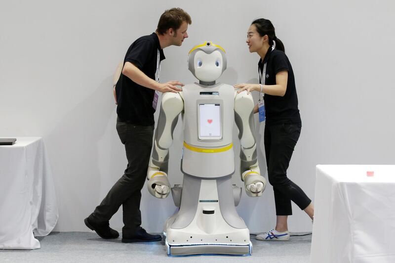 Staff chat next to a P-Care robot at the World Robot Conference (WRC) in Beijing. Reuters