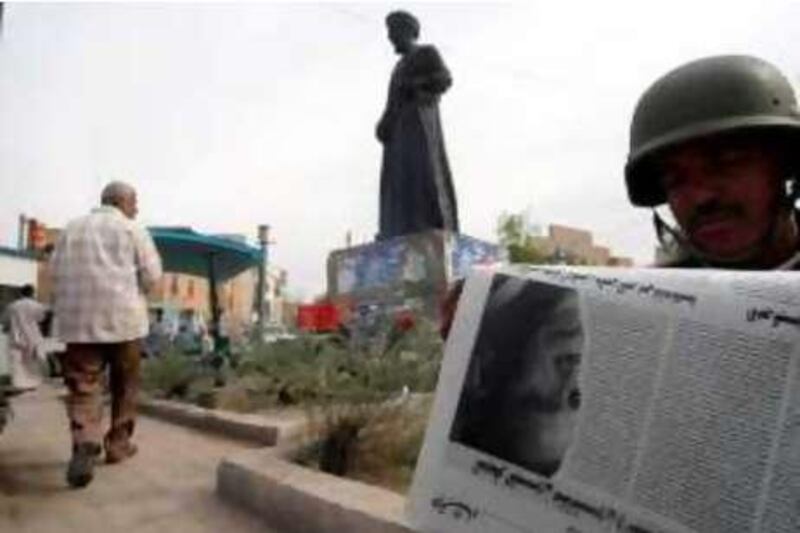 An Iraqi soldier takes a break from his duty to read the morning newspaper featuring the image of  winning US presidential candidate Democrat Barack Obama in the southern city of Basra some 550 kms from Baghdad on November 05, 2008.  Americans emphatically elected Democrat Barack Obama as their first black president yesterday in a transformational election which will reshape US politics and the US role on the world stage. In the background in a statue of the 6th century philogist Al-Farahidi who came from southern Arabia and who died in Basra sometime between 777 and 791. AFP PHOTO / ESSAM AL-SUDANI *** Local Caption ***  640153-01-08.jpg