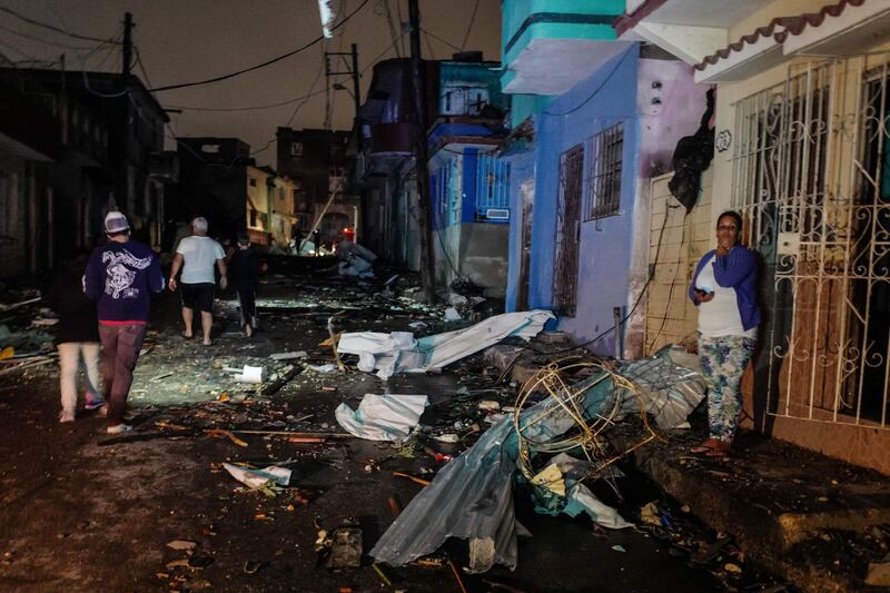 Cubans walk past debris in the tornado-hit Luyano neighbourhood in Havana early on January 28, 2019. AFP