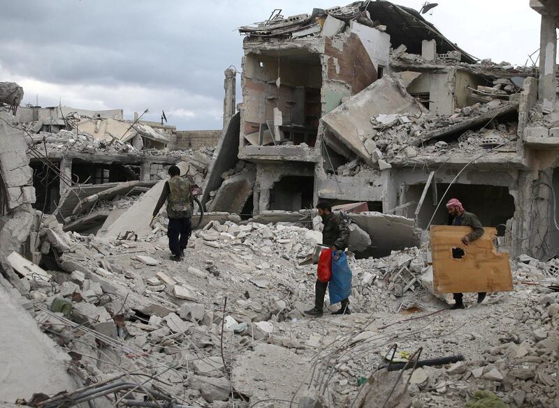 FILE PHOTO: People walk on rubble of damaged buildings in the besieged town of Douma, Eastern Ghouta, in Damascus, Syria March 30, 2018. REUTERS/Bassam Khabieh/File Photo